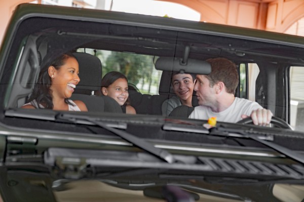 A group of four people is sitting in a car, smiling and laughing.