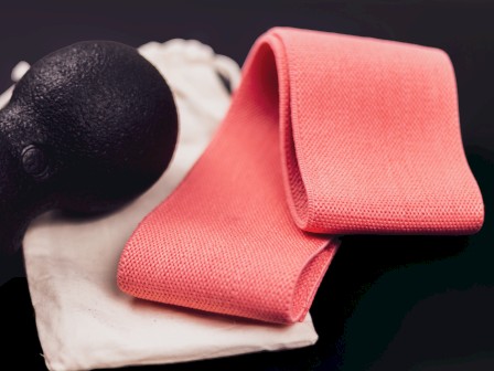 Pink gym towel and cloth, with a black kettlebell resting nearby on a white cloth, set against a dark background.