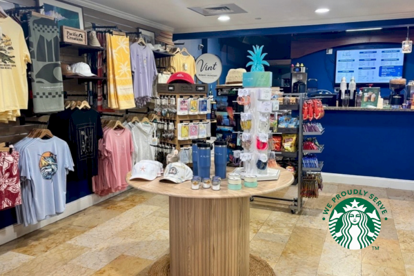 A Starbucks inside a gift shop features apparel, accessories, and souvenirs with a Starbucks logo and a vibrant tropical theme.