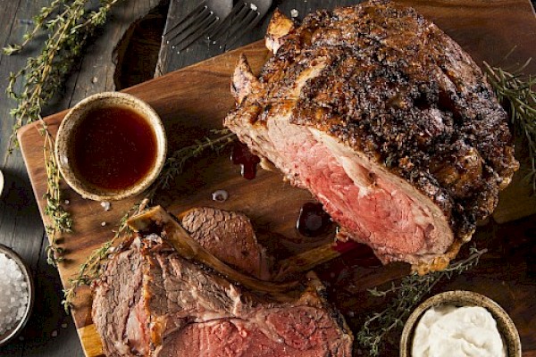A perfectly cooked beef roast, sliced open to show a rare, juicy interior, served on a wooden cutting board with sides nearby.