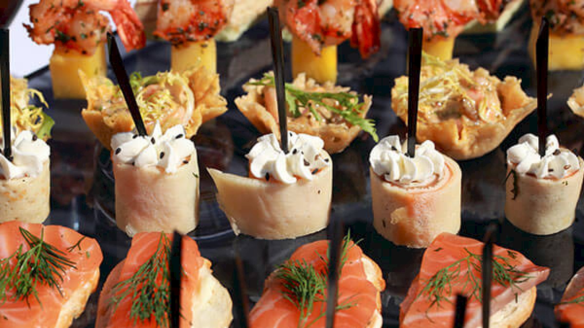 The image shows an assortment of gourmet appetizers, including shrimp, salmon, and various small bites, all beautifully arranged on a platter.