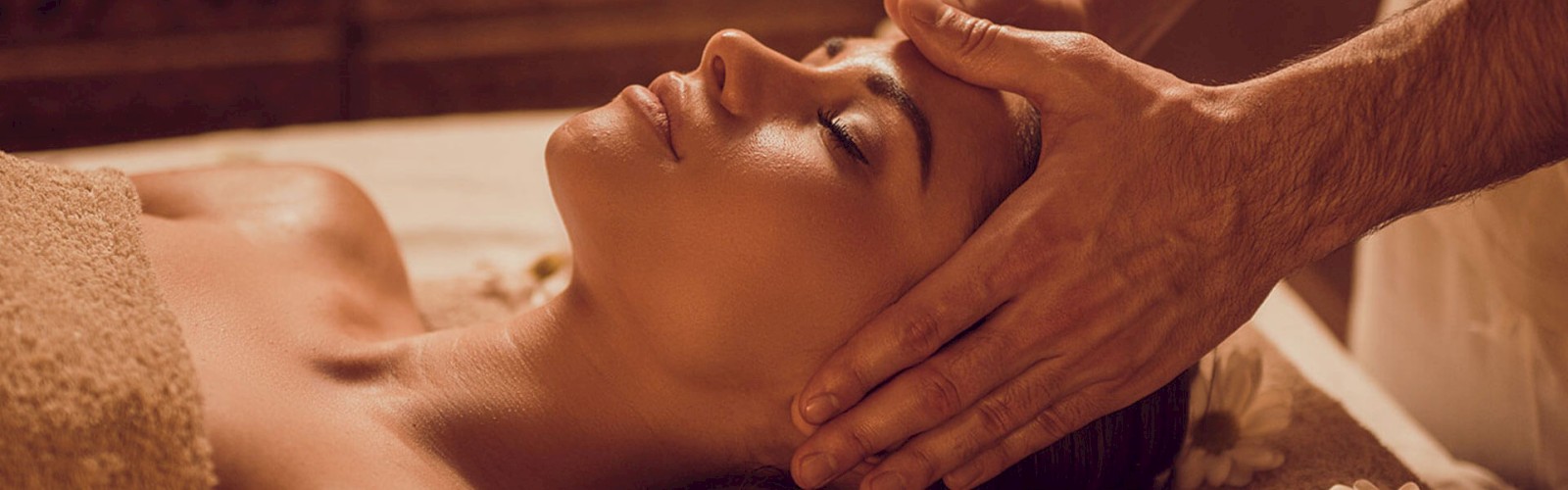 A person is receiving a relaxing head massage while lying on a table, surrounded by a calm and serene atmosphere.