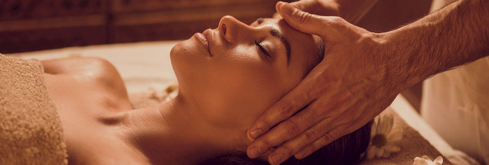 A person is receiving a relaxing head massage while lying on a table, surrounded by a calm and serene atmosphere.