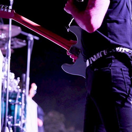 A musician playing an electric guitar on stage during a live concert at night.