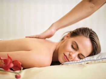 A person is receiving a back massage while lying on a massage table, looking relaxed and content with a peaceful expression.