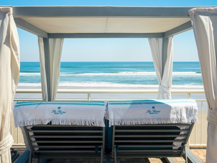 Two lounge chairs under a canopy face the ocean, with 