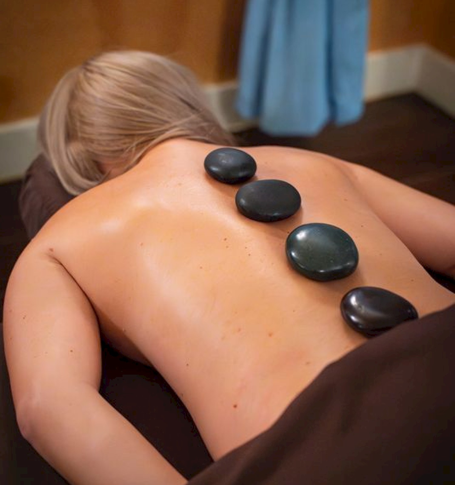 A person receives a hot stone massage on their back in a spa setting for relaxation and relief.