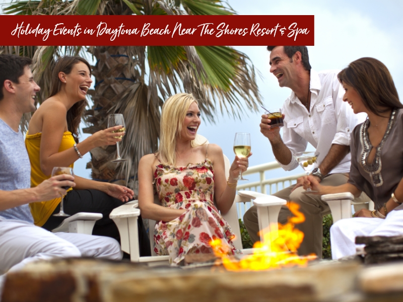 A group of people laughing and drinking wine around a fire pit, with text promoting holiday events in Daytona Beach.