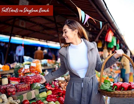 A woman is shopping at an outdoor market, holding a basket filled with fresh produce. The banner reads, 