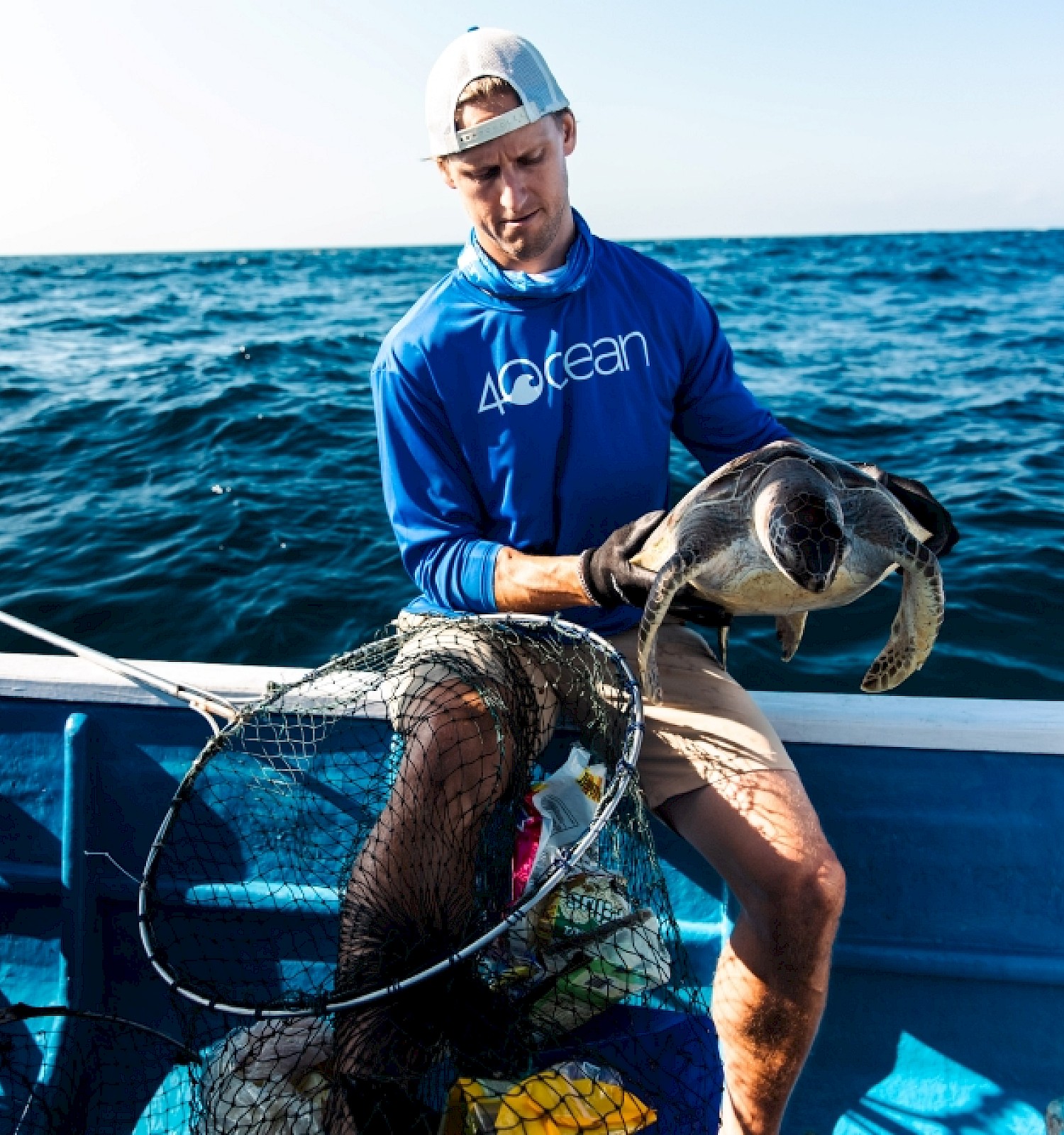 A person releases a sea turtle into the ocean from a boat during a conservation effort.