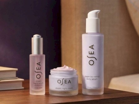 The image shows three skincare products on a wooden surface: a night serum, a dream night cream, and a body serum.