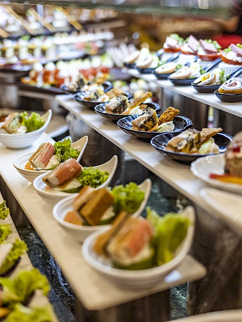 A variety of colorful appetizers and finger foods are displayed on a multi-tiered serving table at a buffet.