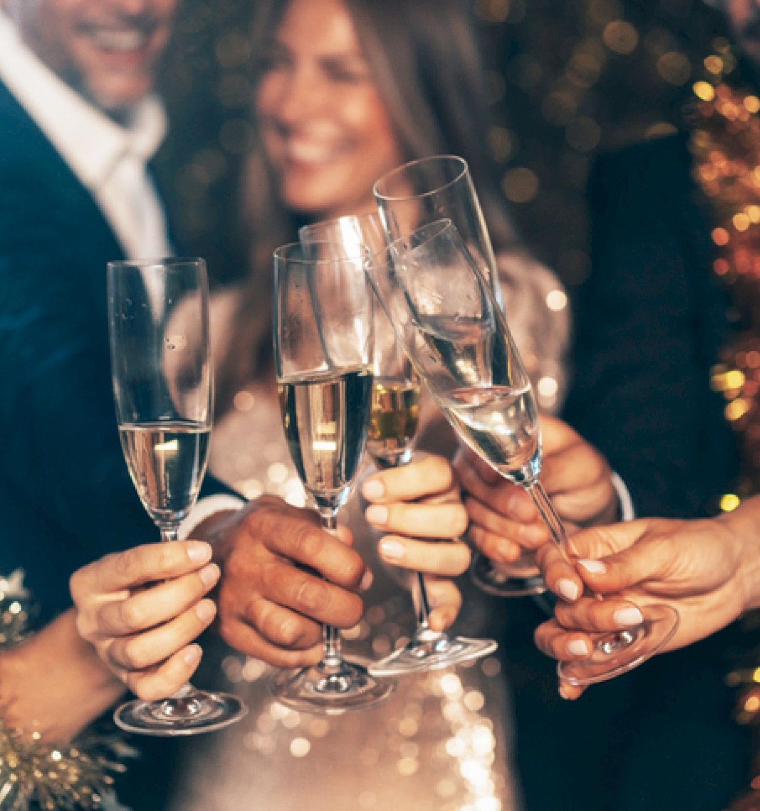 People celebrate with champagne glasses at a festive gathering, likely a New Year's or holiday party.