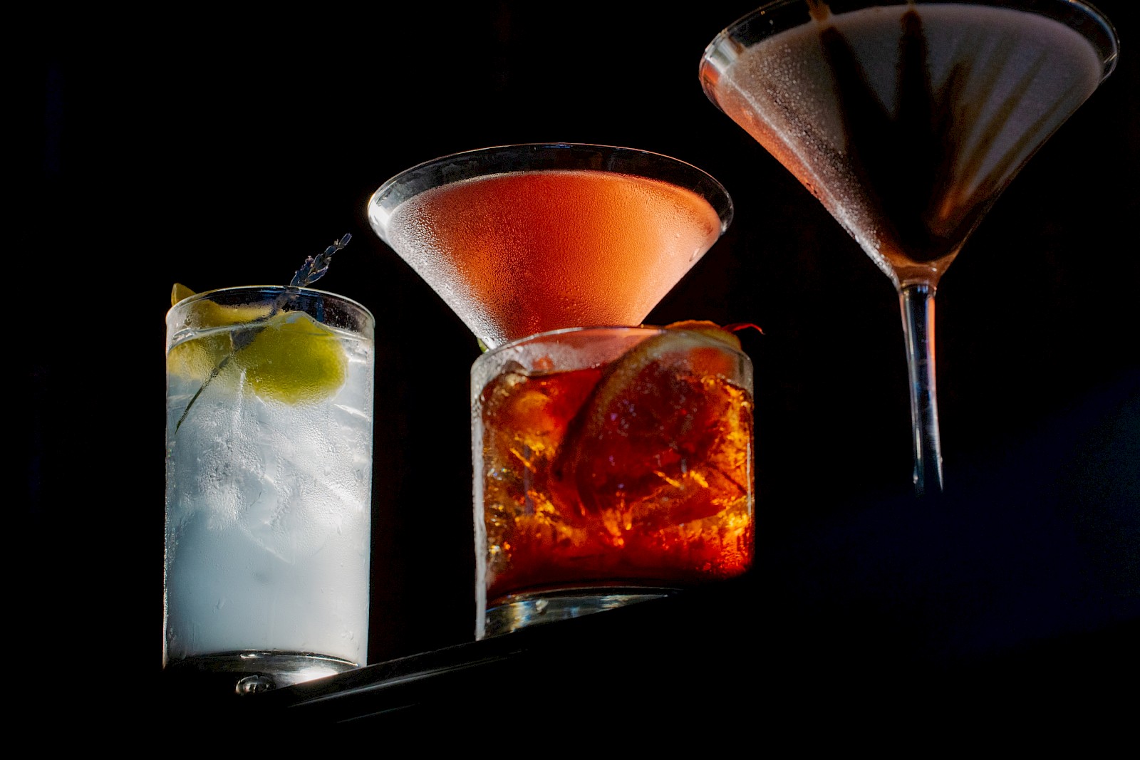 Four different cocktails, each in a unique glass, set against a dark background, creating a sophisticated and inviting atmosphere.