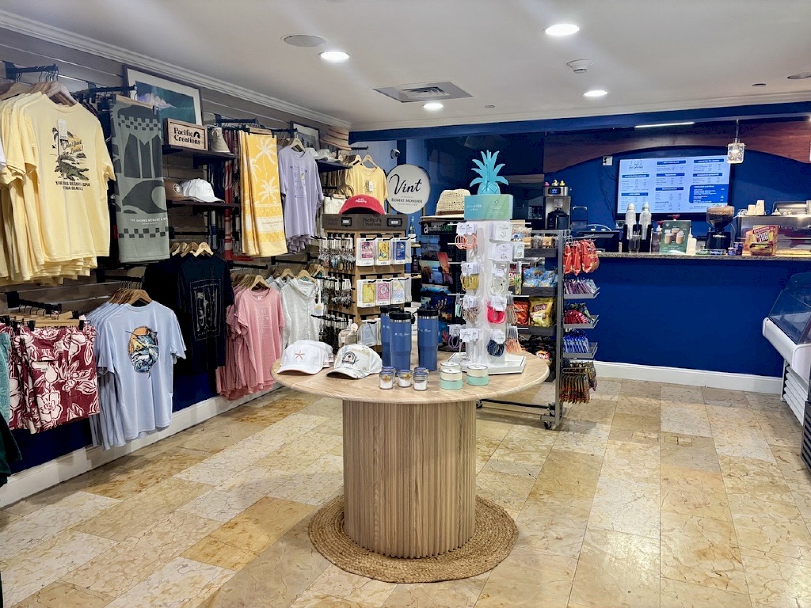The image shows a shop interior with clothing, accessories, hats, and souvenirs displayed near the counter area.