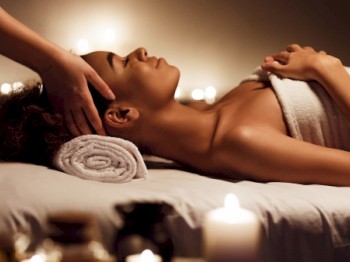 A person is receiving a relaxing massage on a table, covered with a towel. Candles are lit nearby, creating a calming ambiance.