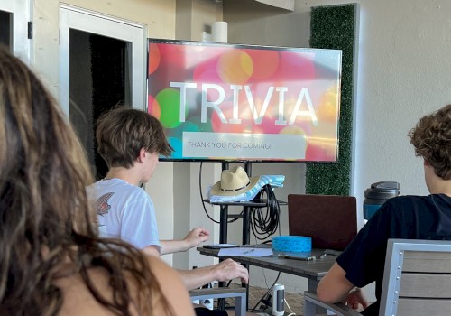 People are seated indoors, facing a screen displaying 