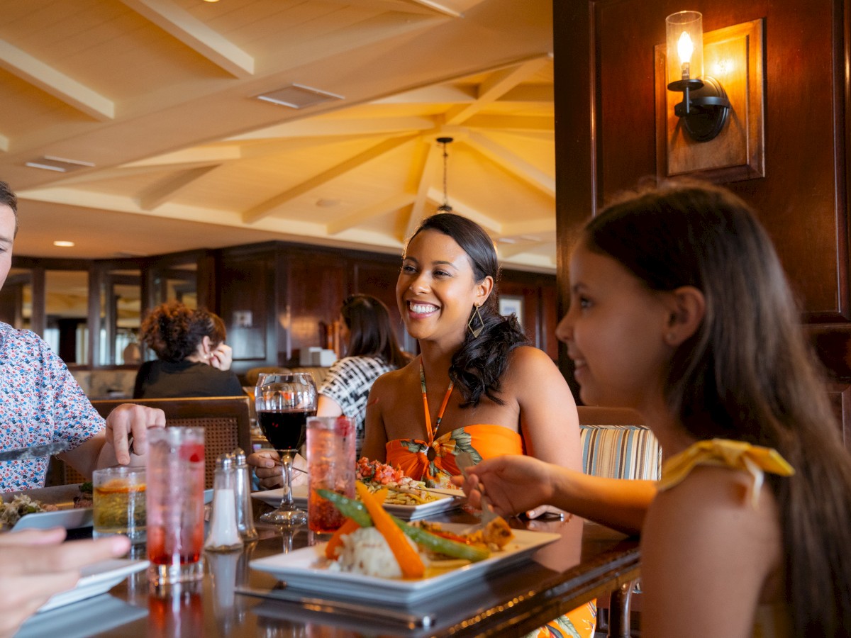 A group of people are dining together in a restaurant, enjoying food and drinks, and engaging in conversation.