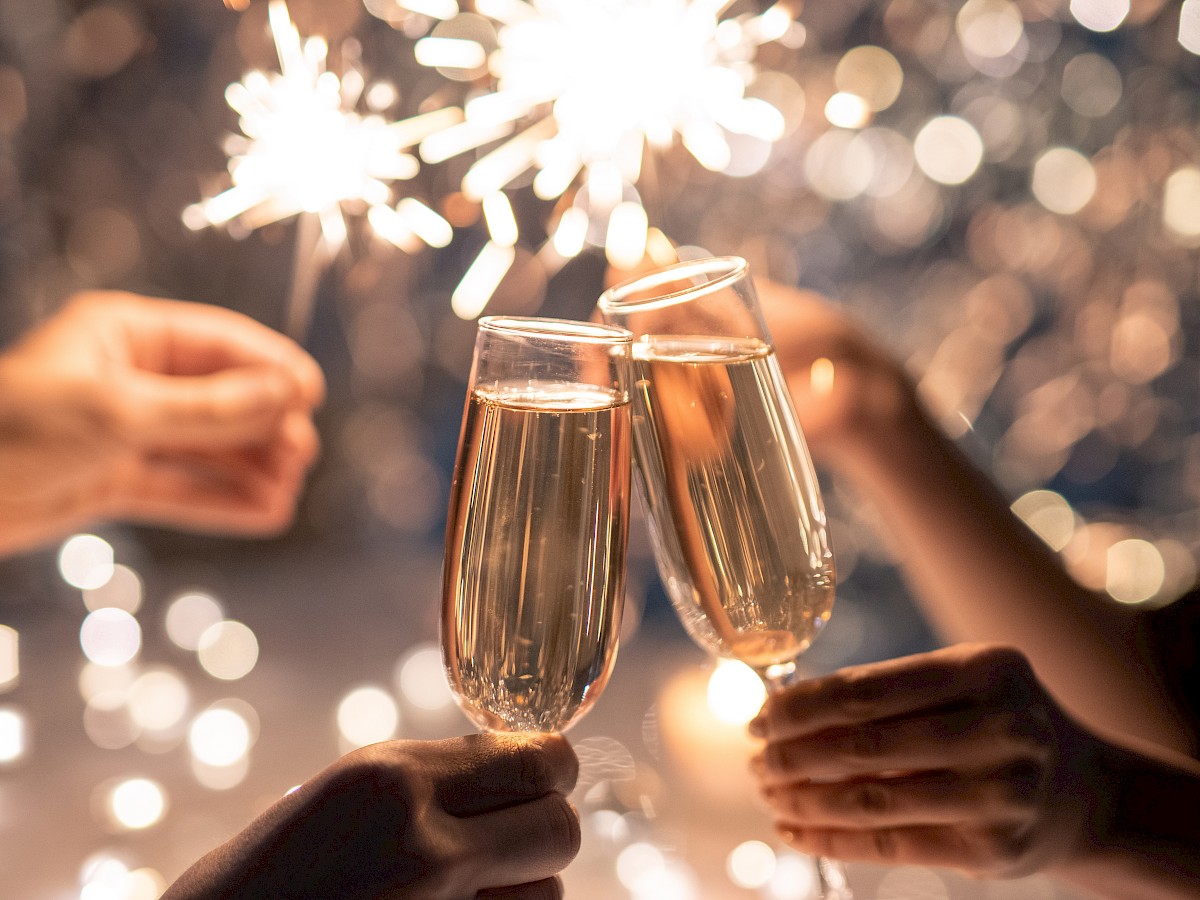 People clinking champagne glasses with sparklers in the background, creating a festive and celebratory atmosphere.