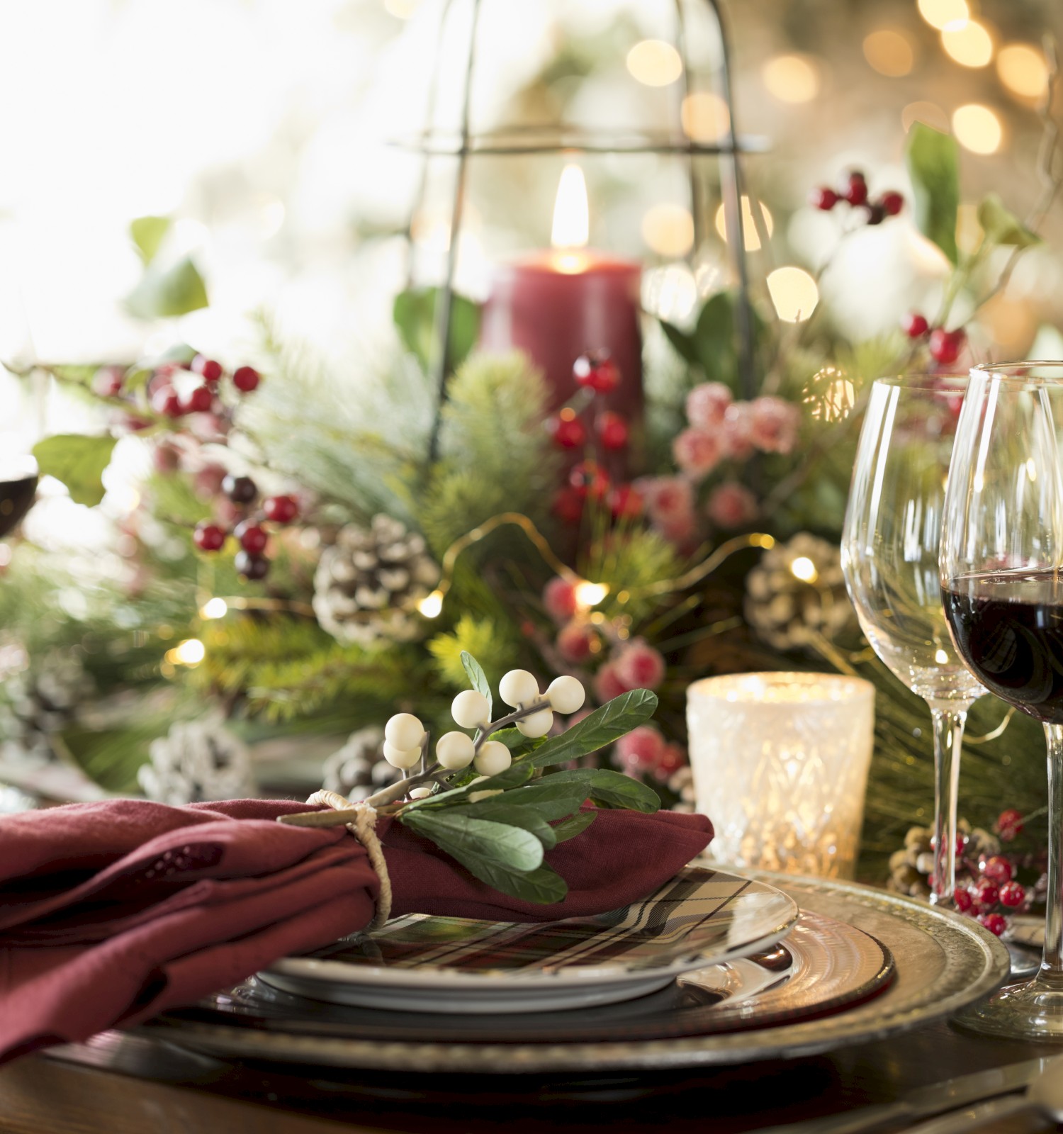 A festive table setting with wine glasses, candles, and decorative greenery, creating a cozy and elegant atmosphere.