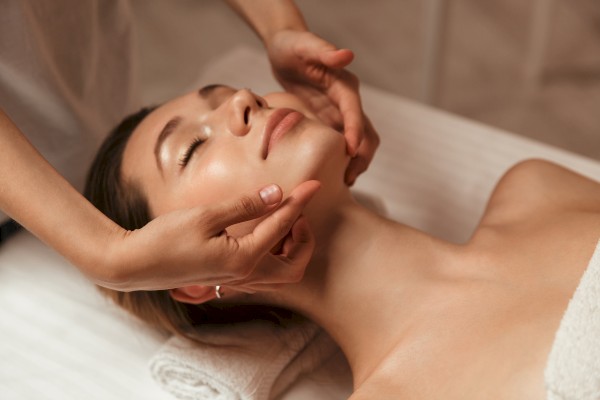 A person receiving a facial massage while lying on a towel, suggesting relaxation in a spa-like setting.