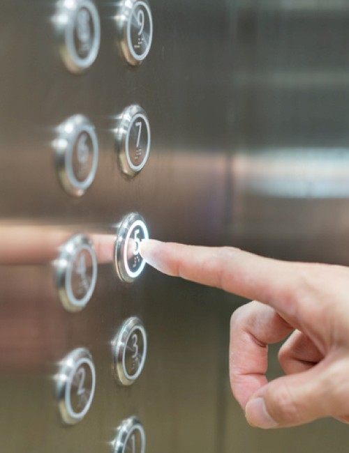 A person is pressing the number 3 button inside an elevator, with several other floor buttons visible on a metallic panel.