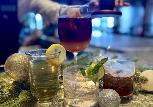 A selection of festive drinks with garnishes on a bar, surrounded by decorative ornaments and greenery.