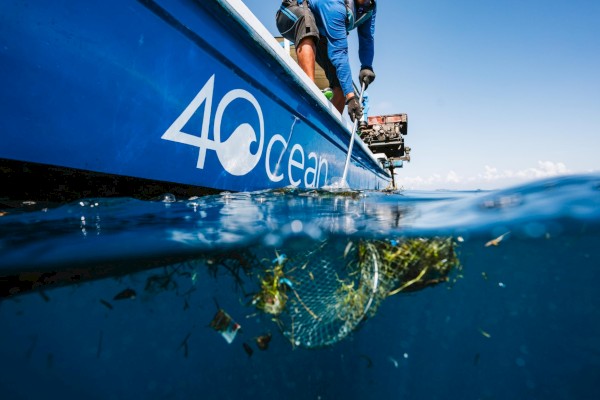 A boat labeled “40 Ocean” floats on the surface while divers or researchers work underwater, revealing a reef or marine life beneath the hull.