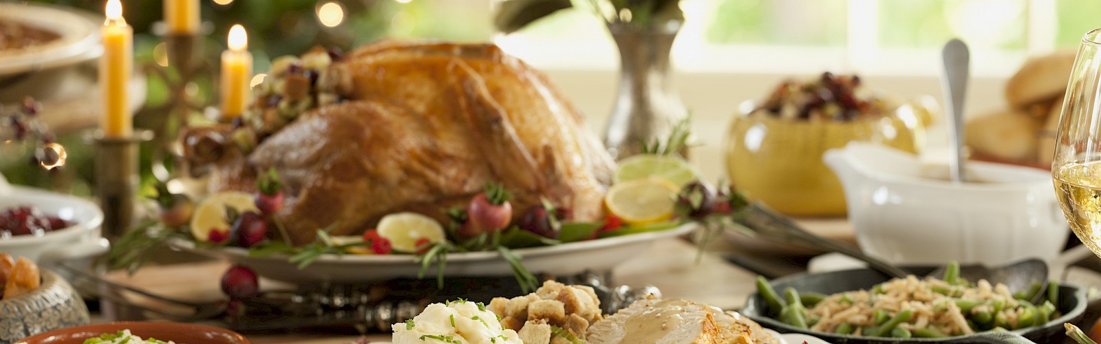 A festive meal features roasted turkey, mashed potatoes, green bean casserole, and various side dishes on a decorated table.