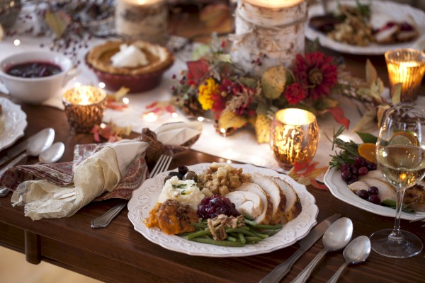 A festive Thanksgiving table with carved turkey, mashed potatoes, green beans, cranberries, and seasonal decorations for dinner.