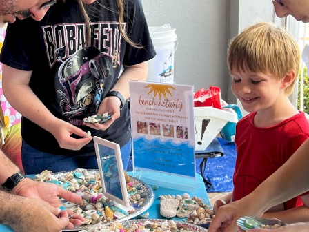 People looking at trays of seashells and small items on a table.