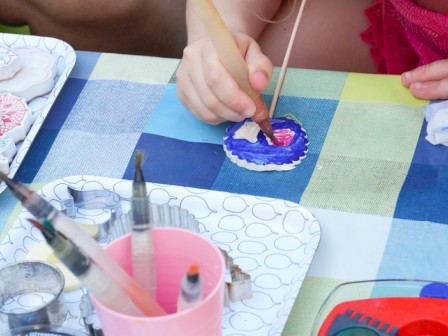 Kids are painting and decorating cookies or cookies with icing at a colorful table.