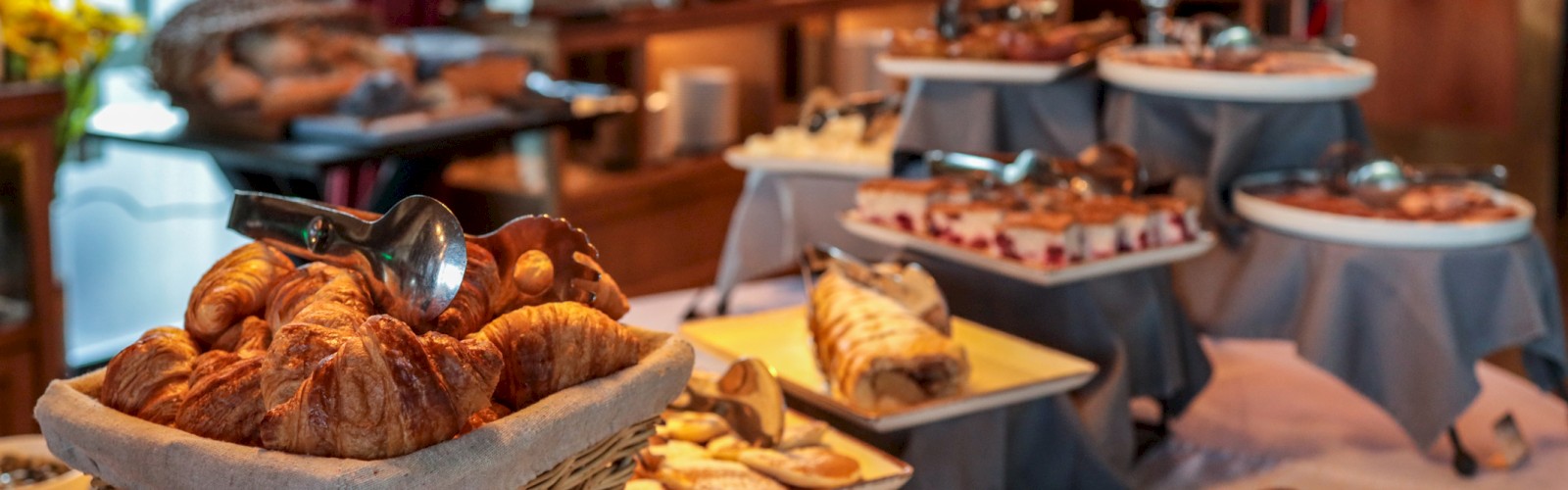A buffet table with assorted pastries, cakes, and desserts in a warm, cozy dining setting.