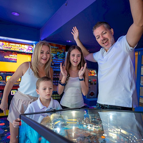 A family plays arcade games at a bowling alley or arcade room; kids and adults smile, with a high-energy, celebratory vibe.